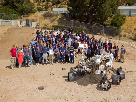 Members of NASA’s Perseverance Mars mission team gather in the Mars Yard at the agency’s Jet Propulsion Laboratory in Southern California with a certificate from Guinness World Records marking the rover distance record on the Red Planet. Positioned in front of the team is OPTIMISM (Operational Perseverance Twin for Integration of Mechanisms and Instruments Sent to Mars), a full-scale engineering model used to plan the rover’s driving routes and science activities on Mars.