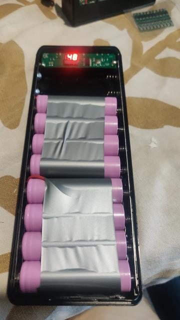A casing holding two sets of four 18650 lithium cells, all wired in parallel. There's some electrical tape holding each set of four together. The charge display reads 48%.