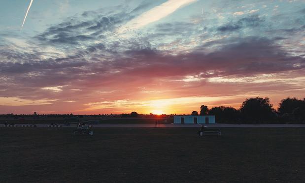Sunset over an open field (former airport) with light clouds in the sky
