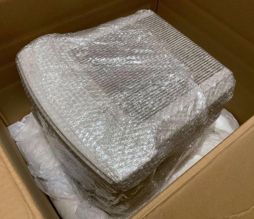a crt sitting in a box, wrapped in bubble wrap, on top of the lower half of expanding foam.