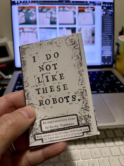 A hand holding a small 8 page magazine the size of a deck of cards. It is titled "I do not like these robots" an explanatory zine by Becky Chambers. Made ahead of my October 2026 book tour by hand and in a fit of pique