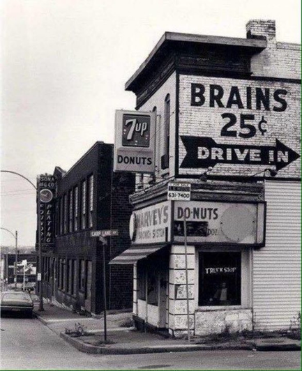 Peeling sign on the side of a dilapidated donut shop reads
BRAINS 25c Drive in