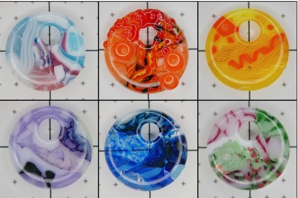 six round pendants with holes for cord in a variety of colors and patterns