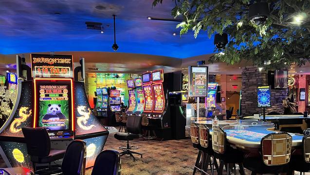 casino interior. slot machines,  craps table, dark blue ceiling, colorful carpet.