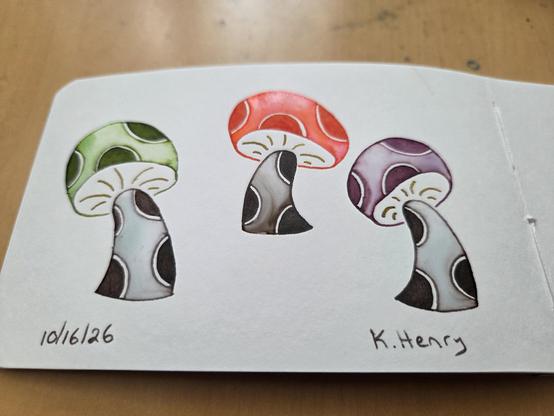 Hand drawn generative/procedural art in ink on an open page of my sketchbook. The abstract pattern looks a bit like three mushrooms with polka dots on their stems and caps. Each cap is a different color.
