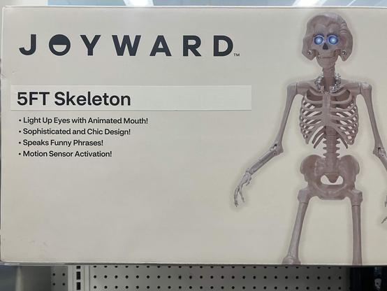 A pharmacy display that reads:

JOYWARD
5ft Skeleton
* Light Up Eyes with Animated Mouth!
* Sophisticated and Chic Design!
* Speaks Funny Phrases!
* Motion Sensior Activation!

Next to it is a picture of a plastic skeleton with eyelashes, a 50s-era harido modeled into the skull, and a costume jewelry necklace and matching earrings made of large chunks of some kind of clear resin.