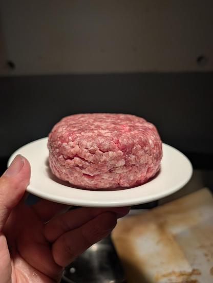 A have holding a saucer holding a 9oz 80/20 beef patty