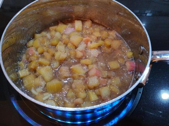 A pot with chopped rhubarb simmers on the stovetop, breaking it down into a tasty jam-like substance