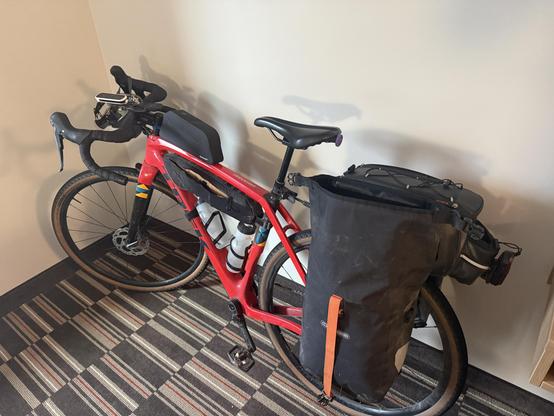Red gravel bike with a couple panniers, frame and top tube bags. Just about all loaded.