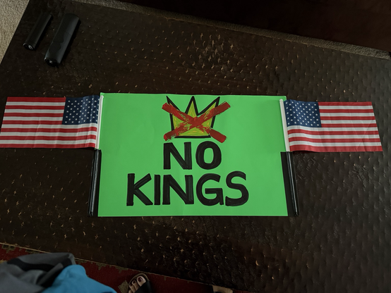 NO KINGS written in bold black font with two US flags taped to the edges. The paper is a bright green.