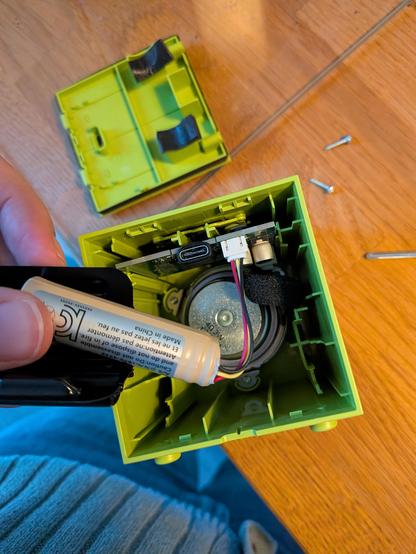 The view into the back of the opened speaker, showing the rear of the speaker cone, the 14500 battery (like an AA size, just higher voltage), and the edge of a PCB with a USB-C connector on it.