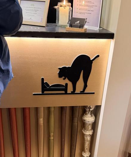 Hotel logo of hissing cat underneath a bed is displayed