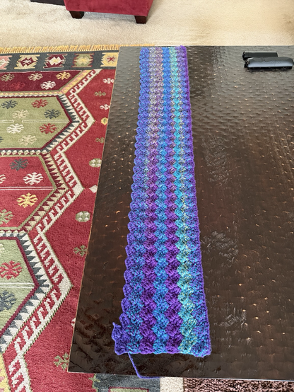A partial throw, about 10" x 48", in various shades of purple, teal, and blues.