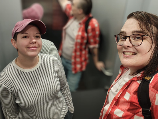 Elevator selfie with me and the brat. I'm giving a toothy grin which shows my slightly yellow chompers.