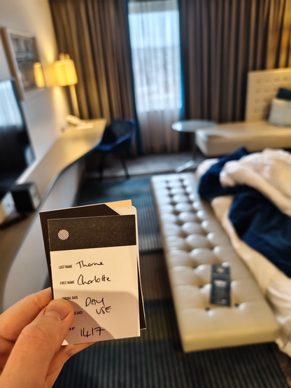 Me holding a hotel room card that says "Arrival Date: Day Use"