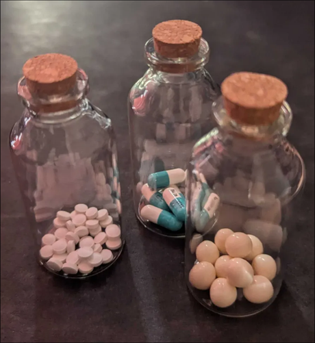 3 glass bottles with corks holding 3 different types of tablets.