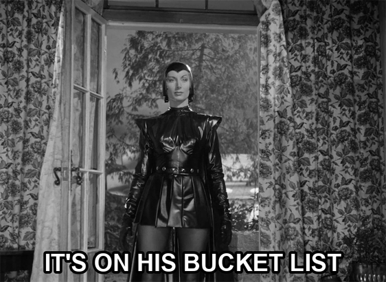screenshot from the film Devil Girl From Mars showing a serious woman wearing a black leather suit, cape, and cowl. Text reads: "it's on his bucket list"