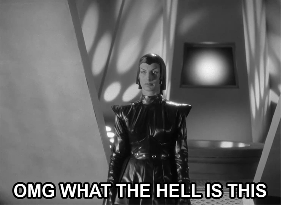 screenshot from the film Devil Girl From Mars showing a serious woman wearing a black leather suit, cape, and cowl. Text reads: "OMG WHAT THE HELL IS THIS"