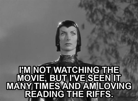 screenshot from the film Devil Girl From Mars showing a serious woman wearing a black leather suit, cape, and cowl. Text reads: "I'm not watching the movie, but I've seen it many times and am loving reading the riffs."