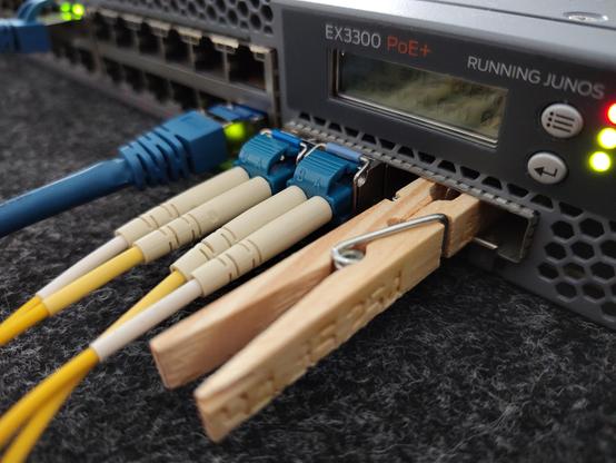 Bild einer Juniper EX3300; eine Wäscheklammer mit eingravierter IP Adresse steckt in 2 SFP Slots