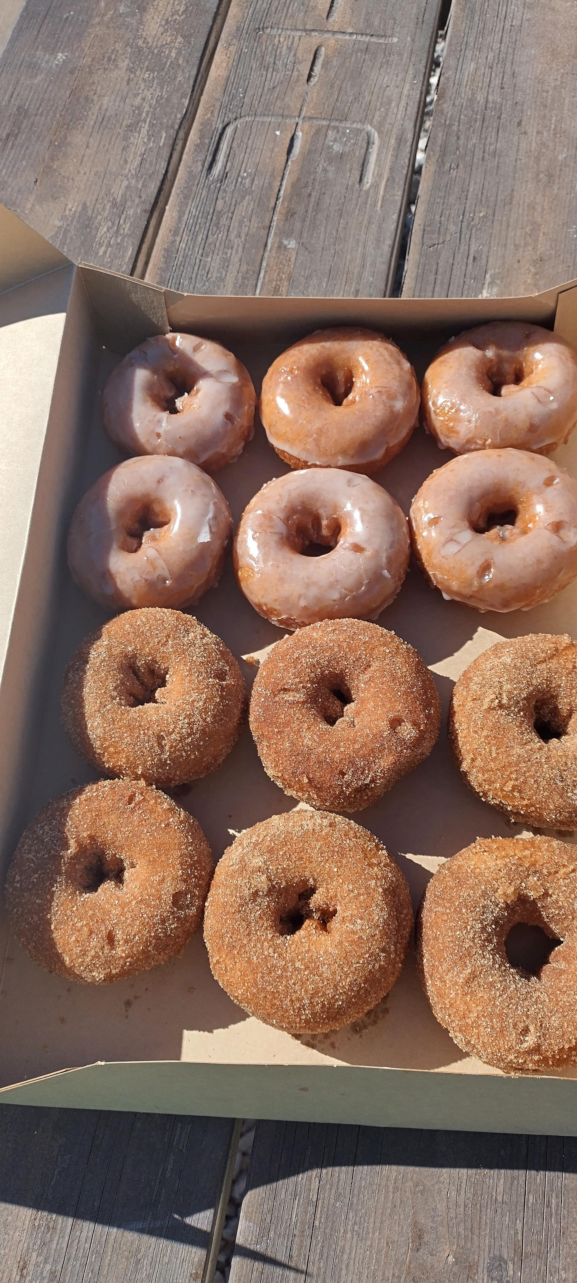 A dozen small donuts, half with cinnamon and sugar and half glazed 